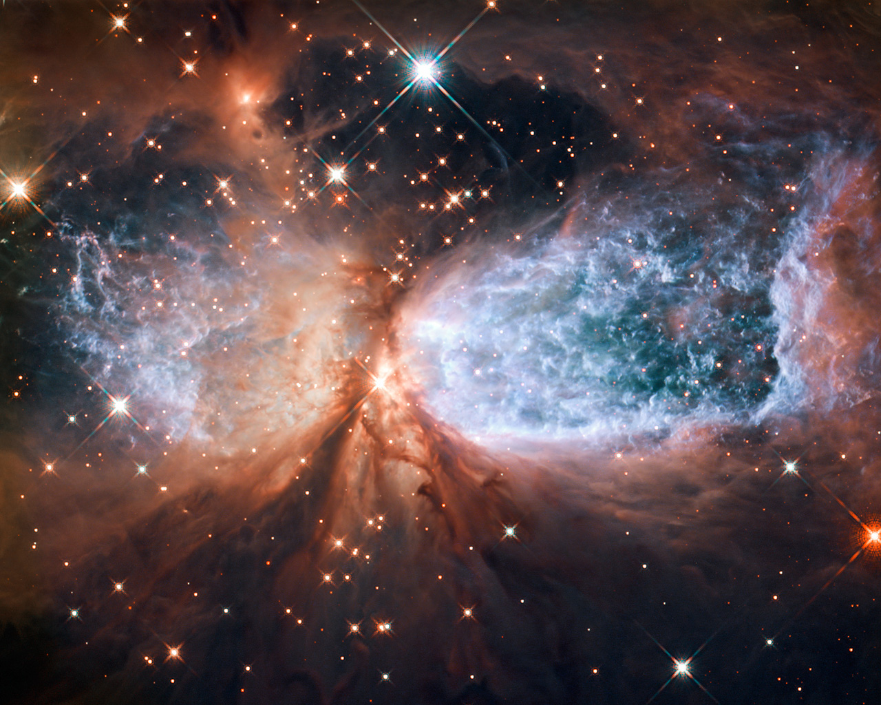 This image from the NASA/ESA Hubble Space Telescope shows Sh 2-106, or S106 for short. This is a compact star forming region in the constellation Cygnus (The Swan). A newly-formed star called S106 IR is shrouded in dust at the centre of the image, and is responsible for the surrounding gas cloud’s hourglass-like shape and the turbulence visible within. Light from glowing hydrogen is coloured blue in this image.