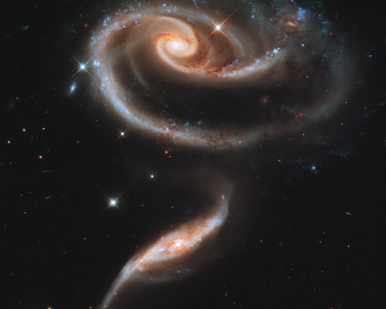 This image of a pair of interacting galaxies called Arp 273 was released to celebrate the 21st anniversary of the launch of the NASA/ESA Hubble Space Telescope.  The distorted shape of the larger of the two galaxies shows signs of tidal interactions with the smaller of the two. It is thought that the smaller galaxy has actually passed through the larger one.